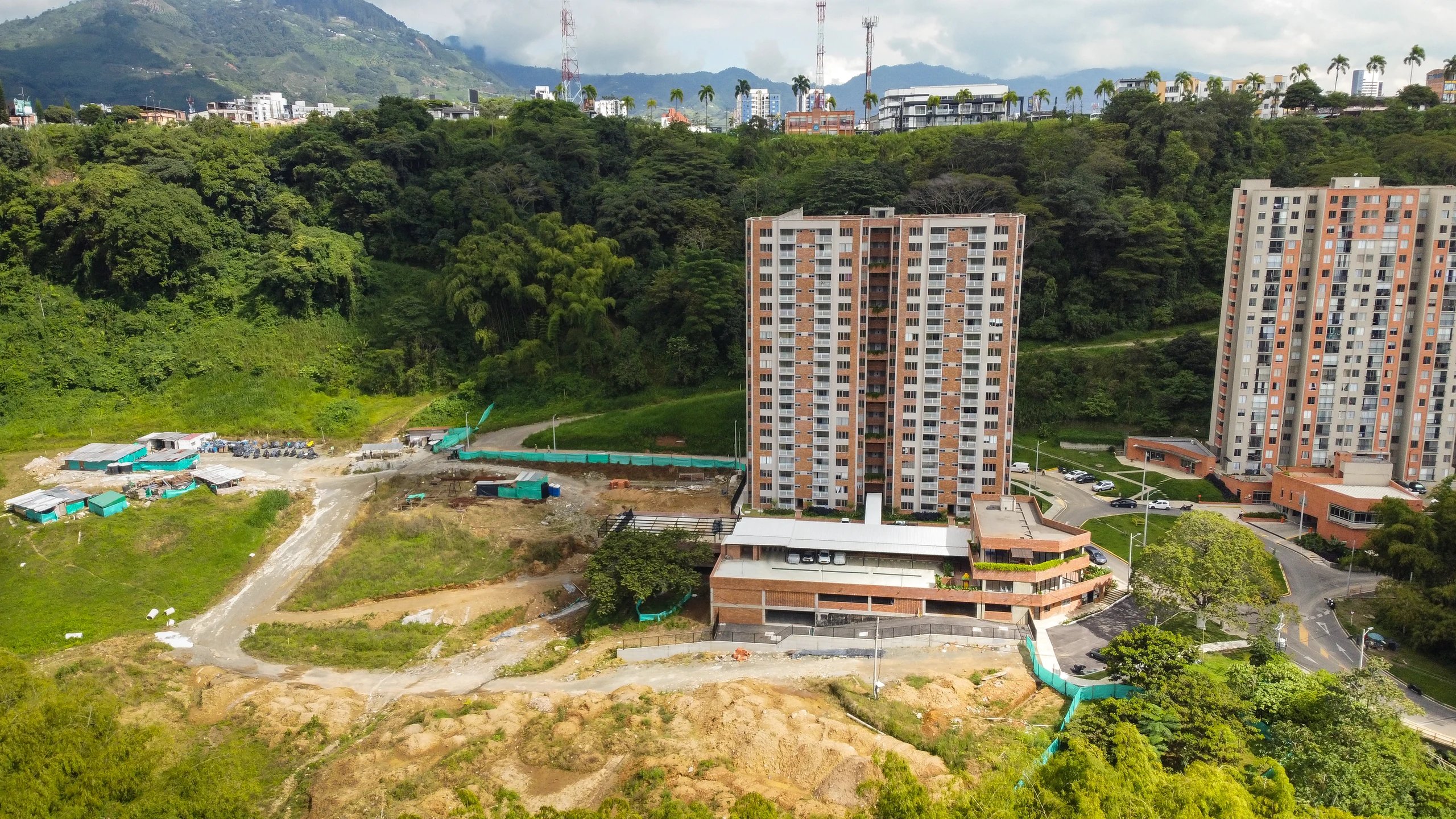 Vista aérea desde el occidente: la torre terminada contra la masa del guadual, y la ciudad de Pereira asomando por encima de la reserva.